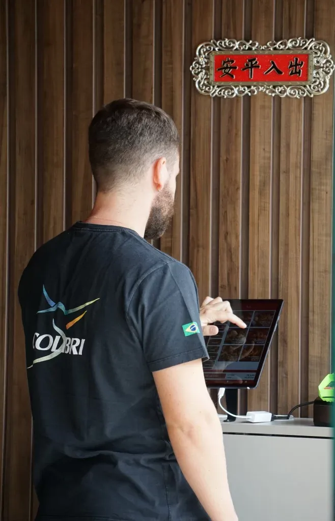 Cliente usando o autoatendimento por totem do Sistema Colibri